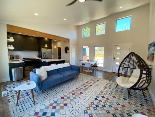 a living room with a blue couch and a kitchen at Timber & Tin H 2Bed 2Bath w Pool & Rooftop Deck in Kanab