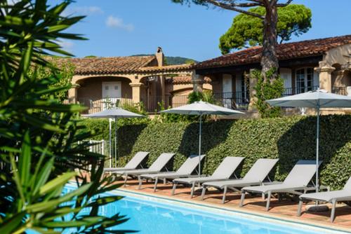 una fila de tumbonas y sombrillas junto a una piscina en Domaine Du Calidianus, en Sainte-Maxime