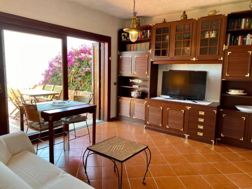 un soggiorno con divano, tavolo e TV di Villaggio Est a Capo Coda Cavallo San Teodoro a San Teodoro