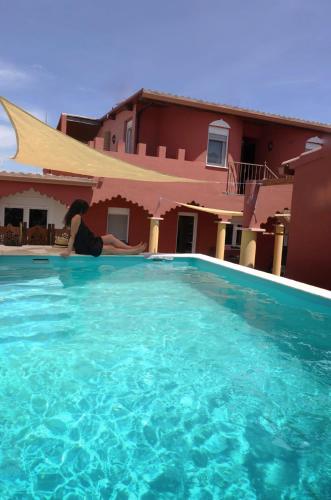 a woman laying in a swimming pool next to a house at Aladin Comfort Country House in Campinho