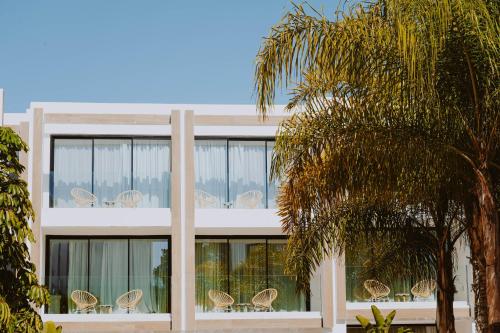 a building with chairs and a palm tree at Nativo Hotel Ibiza in Santa Eularia des Riu