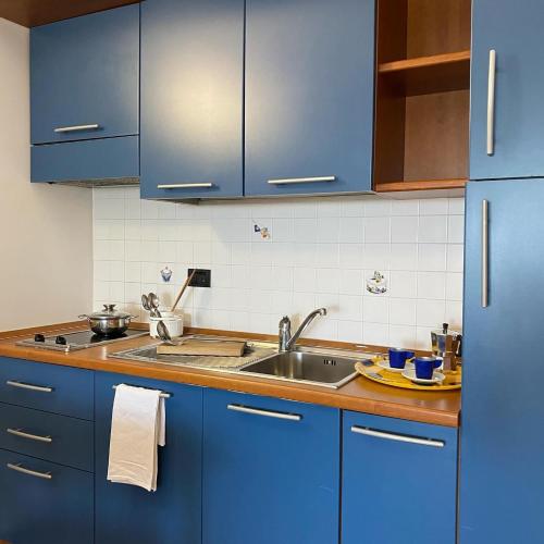 una cocina con armarios azules y fregadero en Jonio Vacanze Residence, en Castellaneta Marina