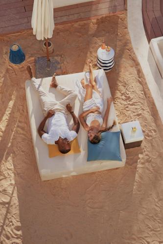 two people laying on a couch in a living room at Nativo Hotel Ibiza in Santa Eularia des Riu