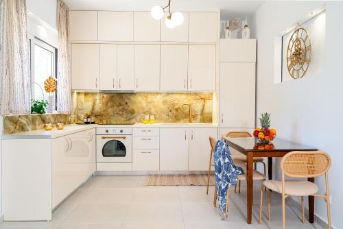 eine Küche mit weißen Schränken und einem Tisch mit Stühlen in der Unterkunft Sueño Seaside Residence in Agia Pelagia