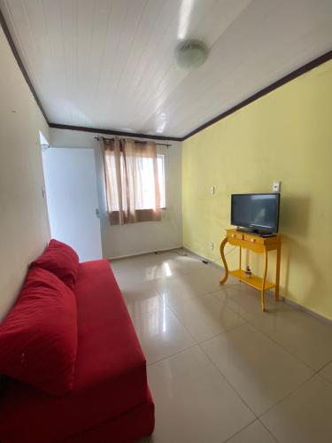 Hoje Apartamentos في فييرا دي سانتانا: غرفة معيشة مع أريكة حمراء وتلفزيون