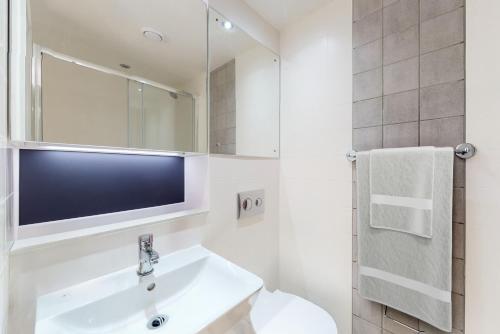 a white bathroom with a sink and a mirror at Premium Studios at Chapter Westminster in London minutes away from The Big Ben in London