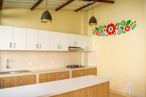 uma cozinha com armários brancos e uma flor na parede em Hostal Perlaschallay em Ayacucho