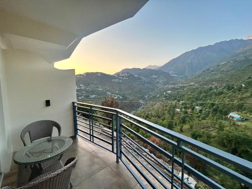 einen Balkon mit einem Tisch, Stühlen und Bergen in der Unterkunft Heryk Hillview Hotel in Dharamshala