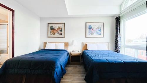 two beds in a hotel room with blue sheets at Commons Inn in Halifax