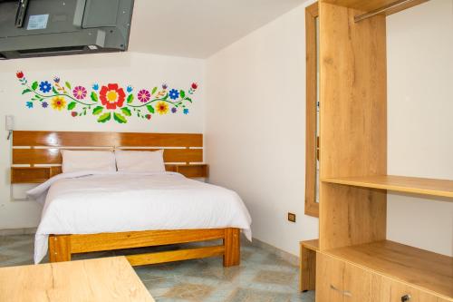 1 dormitorio con 1 cama con una pintura floral en la pared en Hostal Perlaschallay, en Ayacucho