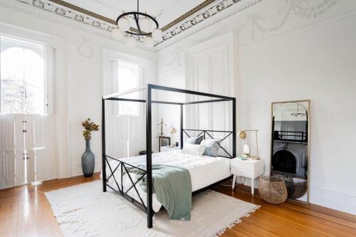 Decadent Luxury - Covington Condo في كوفينغتون: غرفة نوم مع سرير مظلة سوداء في غرفة بيضاء