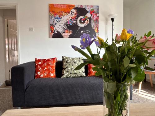 a living room with a couch and a vase with flowers at 1 Newcastle Street in Crewe