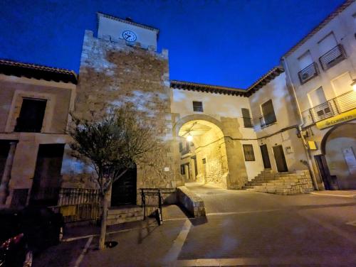 un gran edificio de piedra con una torre de reloj por la noche en Alojamiento 13 Jotas, en Iniesta