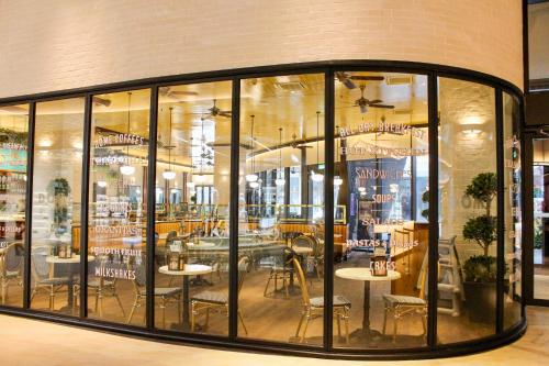 um restaurante com janelas de vidro, mesas e cadeiras em Lucentia Suite by Westlife em Kuala Lumpur