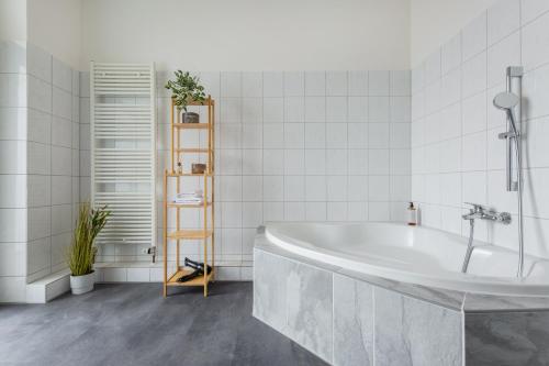 ein weißes Badezimmer mit einer Badewanne und einer Pflanze in der Unterkunft stayVision FS43 Wohnung 5 - 3 Schlafzimmer - 8 Gäste - 2 Balkone - top WLAN in Wuppertal
