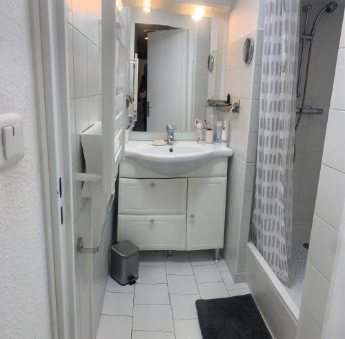 une salle de bain blanche avec un lavabo et un miroir dans l'établissement T3 CLIMATISE 40m2 Piscine Parking PRIVE 2 Chambres Secteur falaises 50 m de la plage Proche centre-port 4 Personnes, au Cap d'Agde