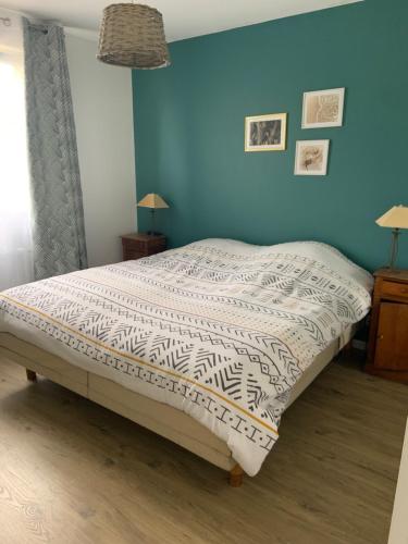 Ce lit se trouve dans une chambre dotée d'un mur bleu. dans l'établissement Maison proche mer, à Moëlan-sur-Mer