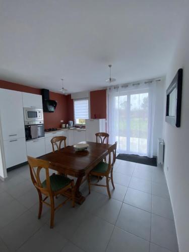 une cuisine et une salle à manger avec une table et des chaises en bois dans l'établissement Maison proche mer, à Moëlan-sur-Mer