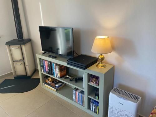 a television sitting on a book shelf with a lamp at Tenuta Le Mandorlaie, Agriturismo in Scansano in Scansano