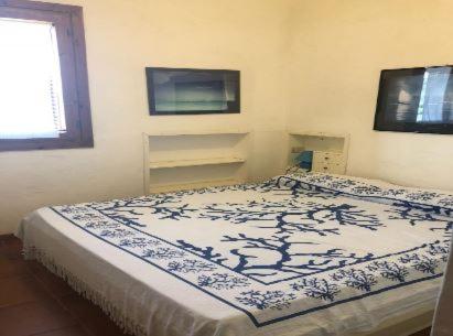 a bedroom with a bed with a blue and white blanket at Villaggio Est a Capo Coda Cavallo San Teodoro in San Teodoro