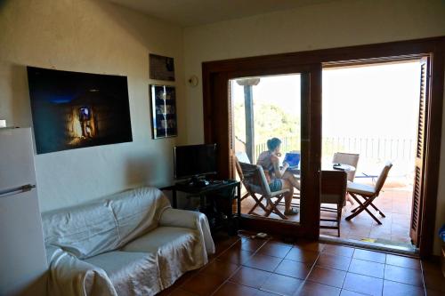 a living room with a couch and a person sitting in a chair at Villaggio Est a Capo Coda Cavallo San Teodoro in San Teodoro