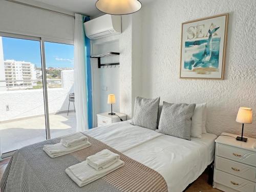 1 dormitorio con 1 cama grande y toallas. en Algarve Sol Beach House, en Quarteira