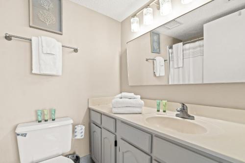 a bathroom with a sink and a toilet and a mirror at Commodore Resort #704 by Book That Condo in Panama City Beach