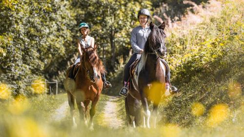 dos personas montando caballos por un camino de tierra en Résidence Le Hameau de l'Ours, en Manigod