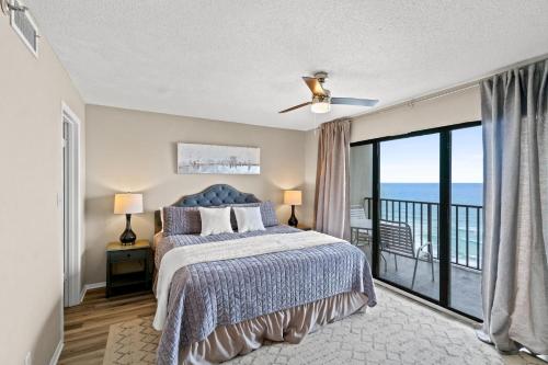 a bedroom with a bed and a balcony with the ocean at Commodore Resort #704 by Book That Condo in Panama City Beach