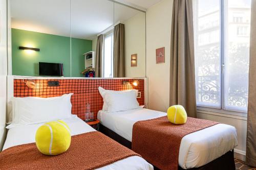 a hotel room with two beds and a window at Hotel Olympic Paris Boulogne by Patrick Hayat in Boulogne-Billancourt