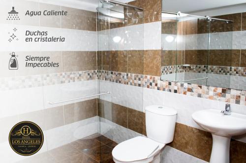 a bathroom with a toilet and a sink at Hotel Los Angeles in Calarcá