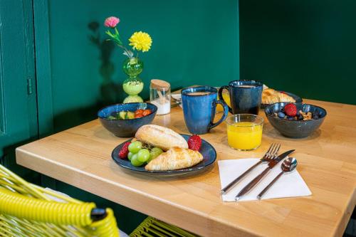 a table with a plate of food and fruit on it at Hotel Olympic Paris Boulogne by Patrick Hayat in Boulogne-Billancourt