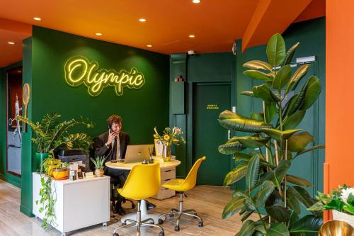 una oficina con un hombre sentado en una mesa con un portátil en Hotel Olympic Paris Boulogne by Patrick Hayat, en Boulogne-Billancourt
