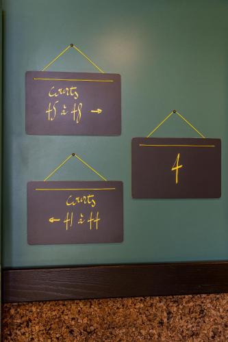 four signs hanging on a wall with writing on it at Hotel Olympic Paris Boulogne by Patrick Hayat in Boulogne-Billancourt