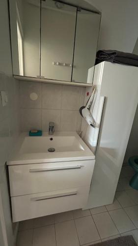 une cuisine avec un évier et un réfrigérateur blanc dans l'établissement Studio Porte Maillot Immeuble Haussmannien, à Neuilly-sur-Seine