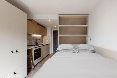 a bedroom with a white bed and a kitchen at Premium Studios at Chapter Westminster in London minutes away from The Big Ben in London