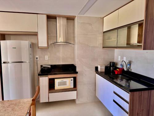a kitchen with a white refrigerator and a microwave at Ondina Apart Hotel Residences in Salvador