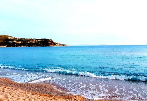 a beach with blue water and a rocky shoreline at Philoxenia Guest Studio in Himare