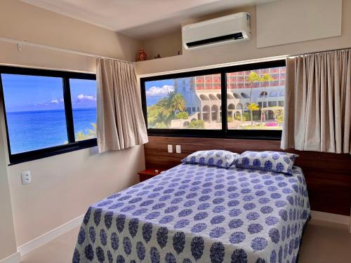 a bedroom with a bed and two large windows at Ondina Apart Hotel Residences in Salvador