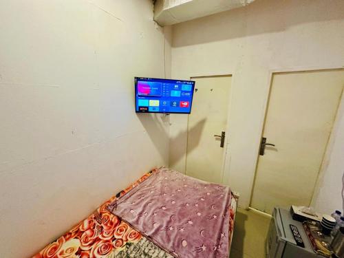 um pequeno quarto com uma televisão na parede em Couples Room with Window smart TV Fridge em Dubai