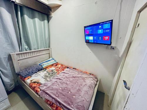 uma pequena cama num quarto com uma televisão na parede em Couples Room with Window smart TV Fridge em Dubai