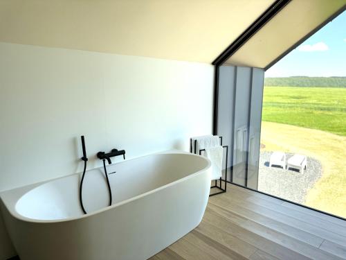 a white bath tub in a bathroom with a large window at Durbuy insolite - Romantic Escape in Durbuy
