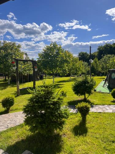 un parque con árboles en el césped y un parque infantil en Chalet "Family" en Suskovo