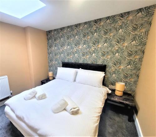 ein Schlafzimmer mit einem großen weißen Bett mit Handtüchern darauf in der Unterkunft Friary House Serviced Apartments by Roomsbooked in Gloucester