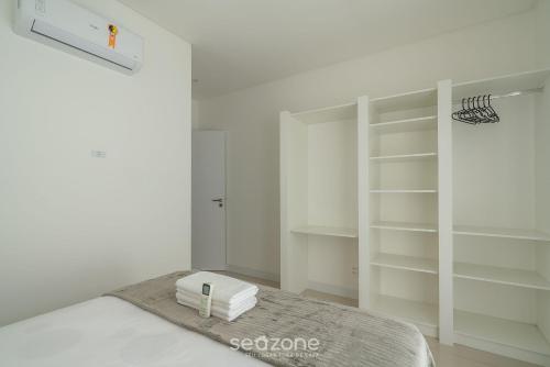 a white bedroom with a bed with white shelves at Apto 3Q c/ piscina e acad. 180m - LTT803 in Piçarras