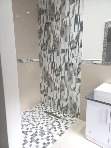 een badkamer met een douche en een zwart-witte tegelvloer bij Caribbean Estates Villa B9 on Barbados in Port Edward