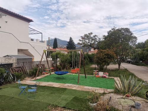 un parque infantil con columpio en un patio en Appartement, prive terrasse, parking et jardin, en Le Boulou