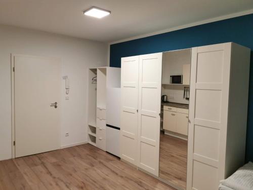 une pièce vide avec des armoires blanches et une cuisine dans l'établissement Ferienwohnung 306 am Kasinopark, à Georgsmarienhütte