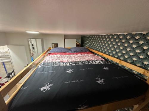 un lit dans une chambre avec un couvre-lit noir et un cadre de lit dans l'établissement Studio equipé, lumineux a Paris, à Paris