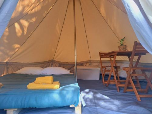 a bed in a tent with a table and a desk at Bearsu Nature Almoxarife in Horta